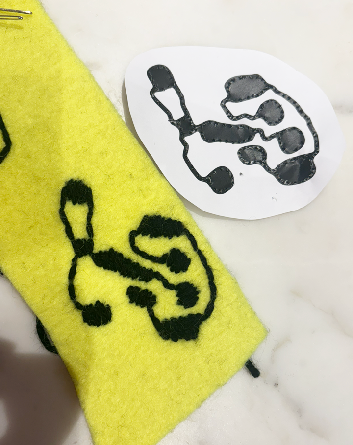 Ornate captial P embroidered in black onto yellow wool