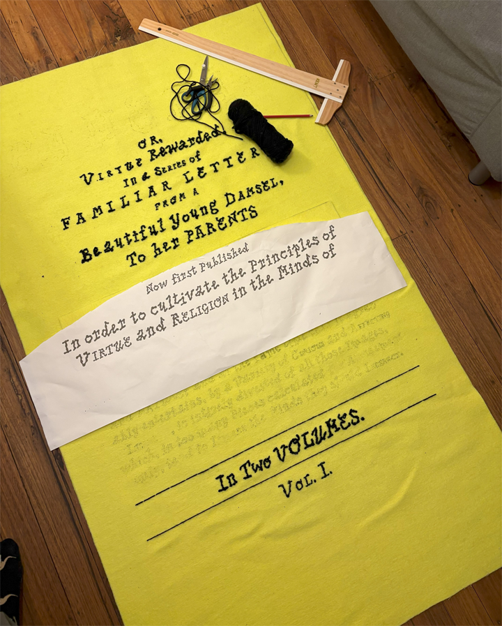 Large piece of yellow wool in process of having black embroidery applied to it